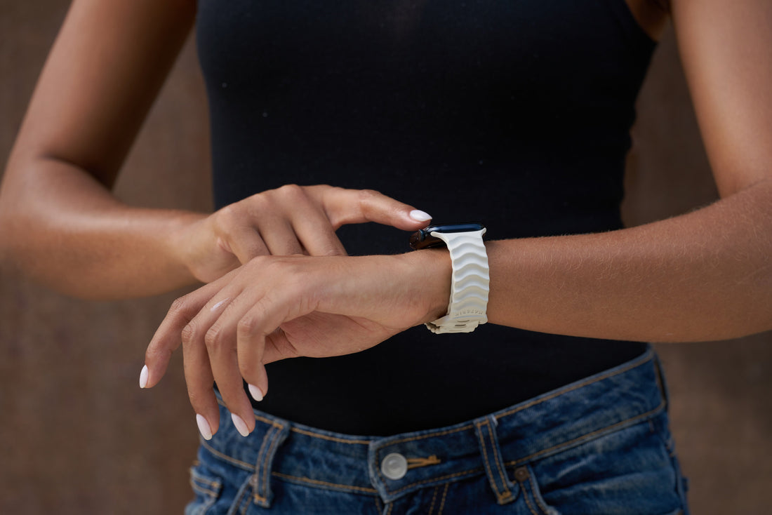 Woman checking her Apple Watch wearing the Materik Ripple band in Ivory Sand