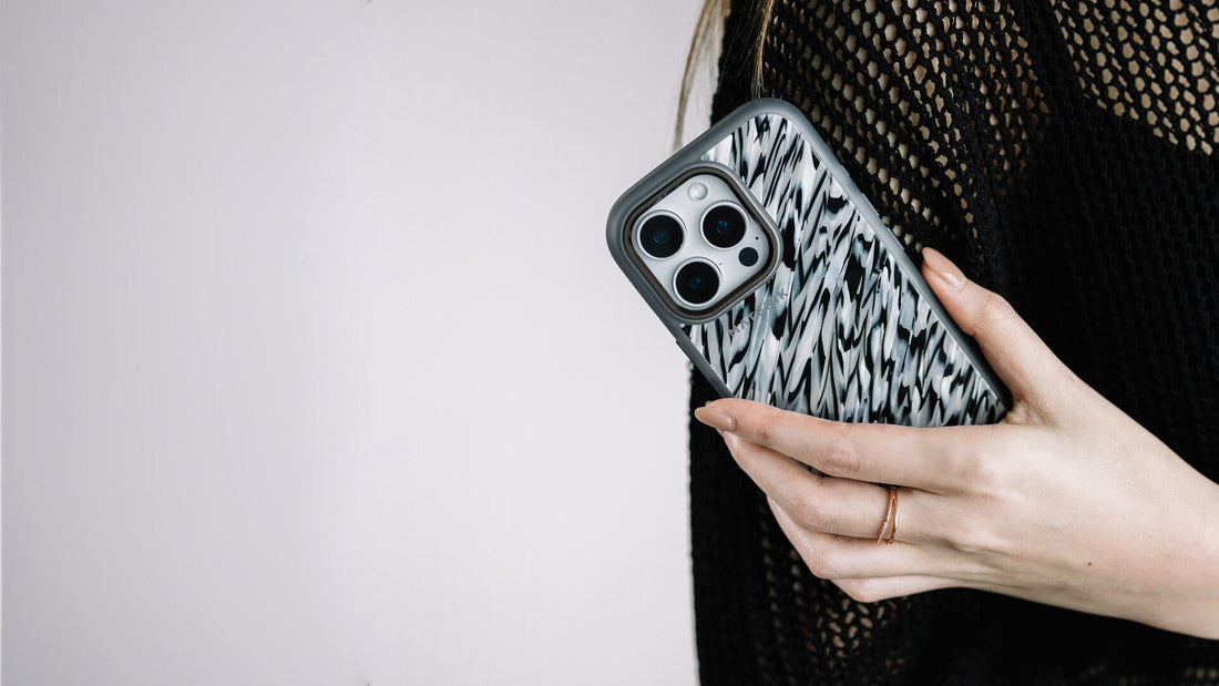 A hand holding an iPhone in a Materik PureCase, showing the handmade Italian pattern on the back